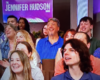 Audience members smiling and looking toward the stage on The Jennifer Hudson Show set, with the show's purple logo in the background.