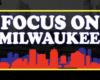 Banner reading 'FOCUS ON MILWAUKEE' with a yellow border and red/blue skyline silhouette against a dark background.