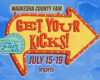 Bright yellow arrow sign reading 'Get Your Kicks!' for Waukesha County Fair, July 15–19, against a blue sky background.