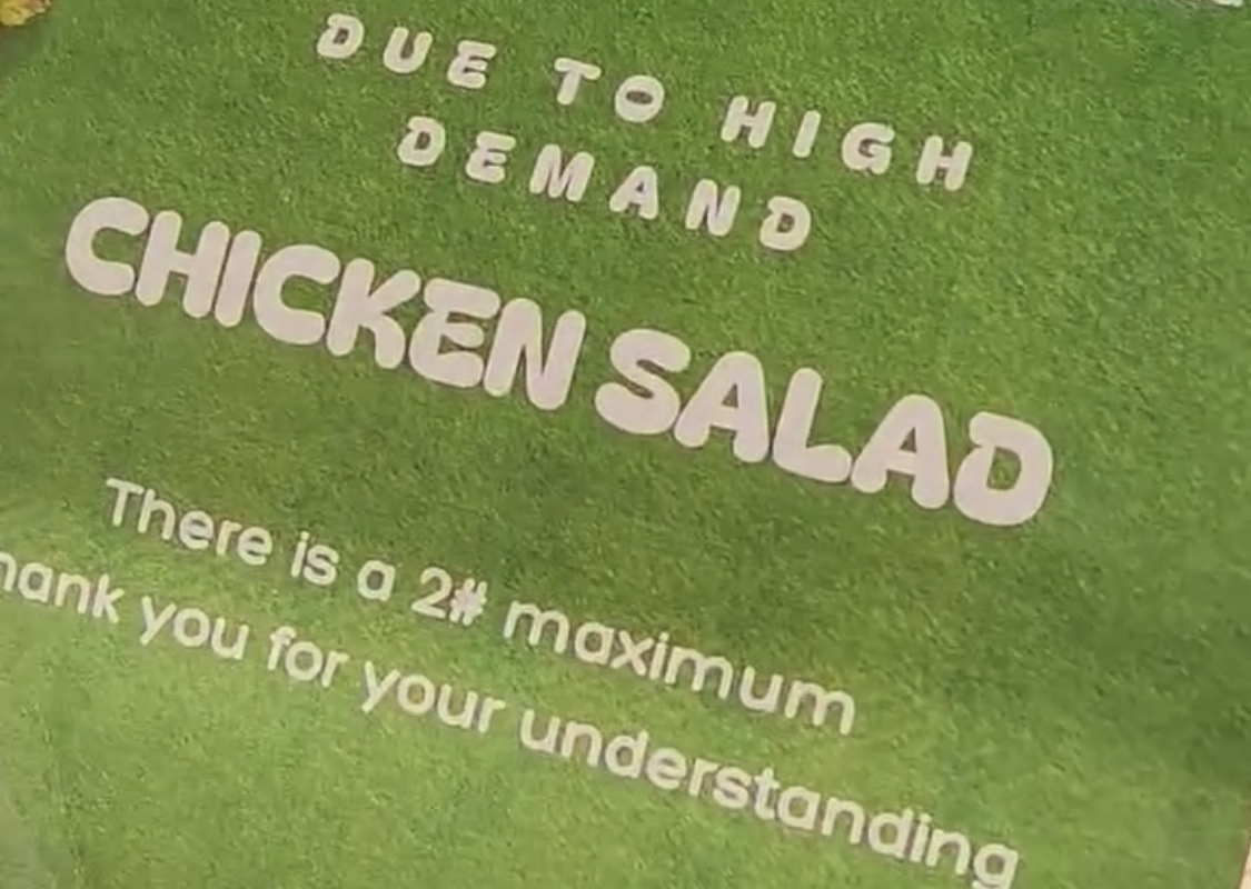 Sign on green grass announcing chicken salad: due to high demand, there is a 2-pound maximum; thank you for your understanding.