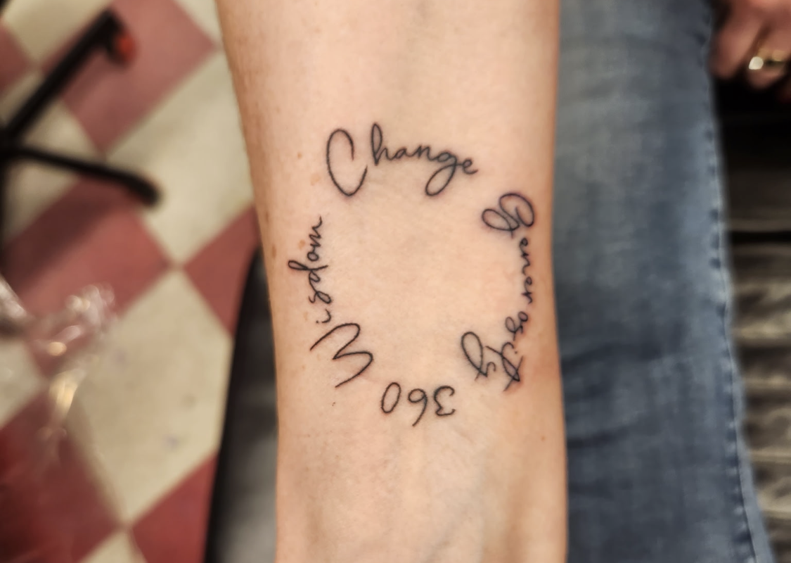 Forearm tattoo with words arranged in a circle; the top reads 'Change,' suggesting a theme of transformation and growth.